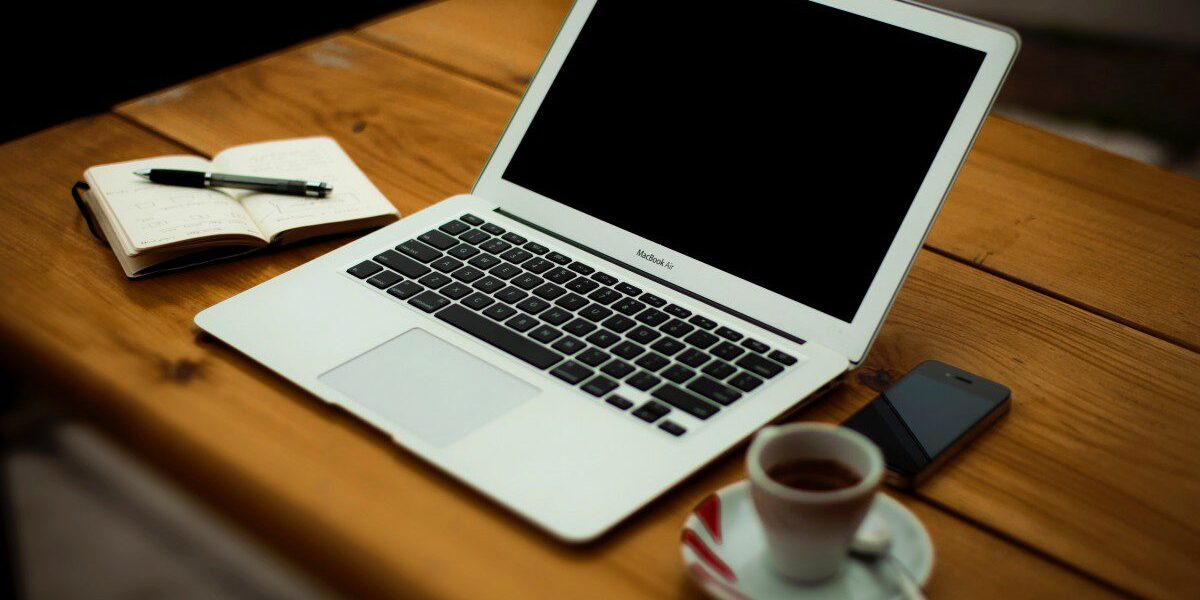 A laptop with a journal and coffee