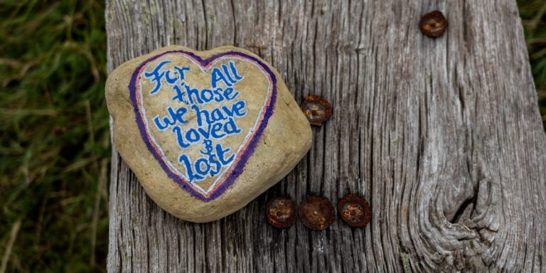 Photo of a rock painted with a message of grief