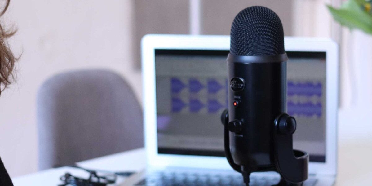 Yeti mic in front of a laptop with a person speaking into it.