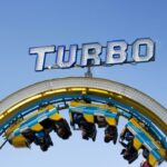 person riding on yellow and blue Turbo roller coaster