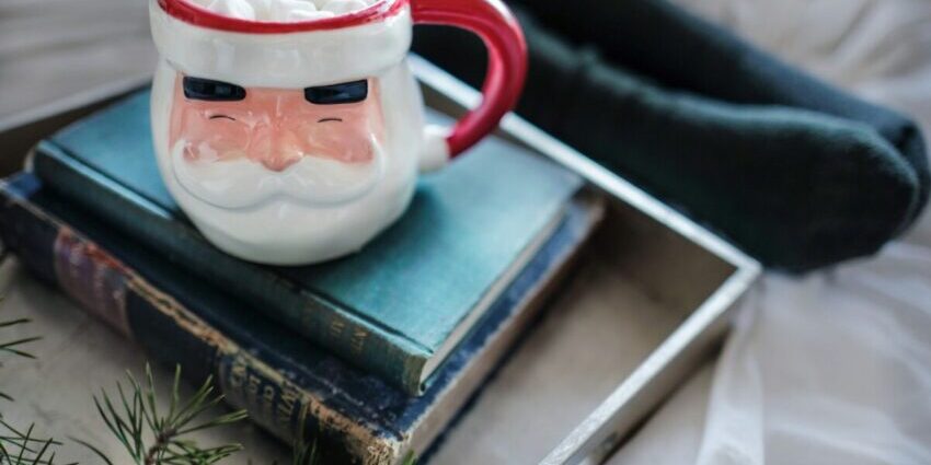 white and red ceramic mug on books